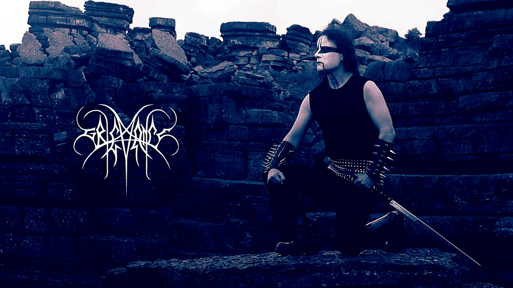 Koraxid de Grievance entre formações rochosas, com corpse paint e estética de black metal