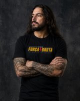 Homem metaleiro tatuado de braços cruzados com T-shirt Força Bruta
